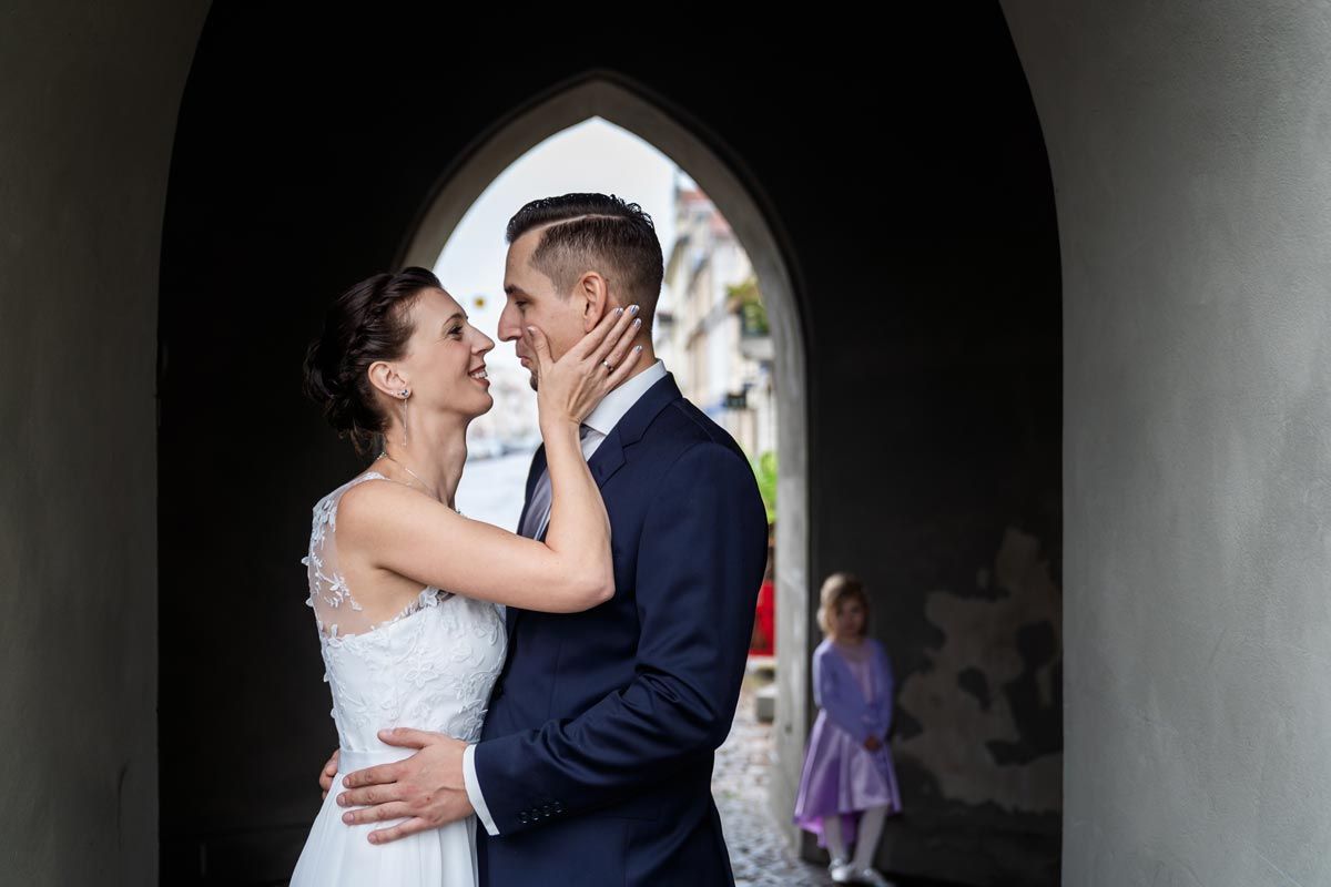 Fotograf Standesamt: Zärtlicher Moment des Brautpaares unter einem Bogengang.